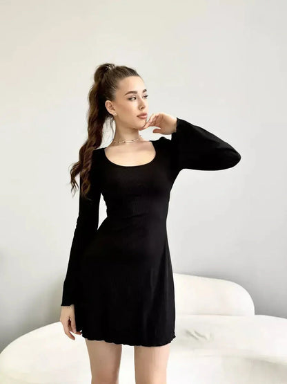 Model showcasing the Noir Flare mini black dress with long sleeves and a deep square neckline.