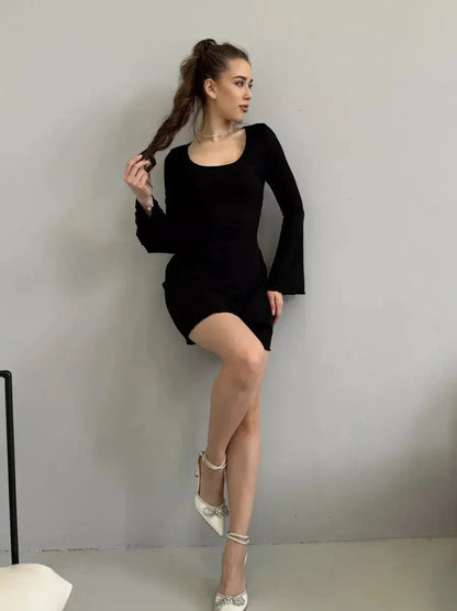 Model showcasing the Noir Flare black mini dress with flared long sleeves and a square neckline, perfect for special occasions.