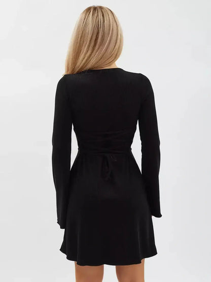 Back view of a woman wearing a Noir Flare Mini Dress with long flared sleeves and a tie waist, showcasing a sleek black design.