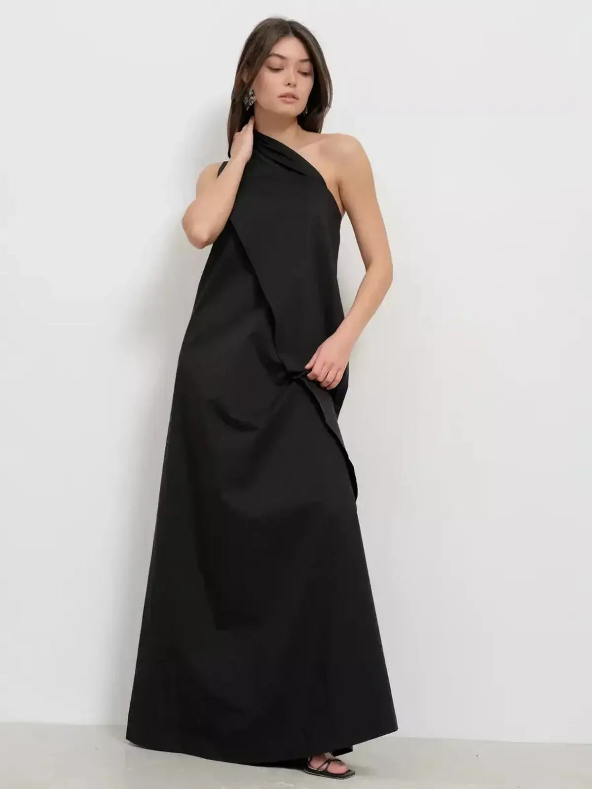 Elegant black one-shoulder maxi dress featuring sculptural drape, perfect for sophisticated evening occasions.