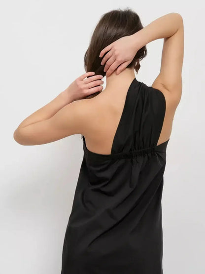 Back view of a woman wearing a black one-shoulder Noir Fold Maxi Dress, showcasing its elegant draped design.