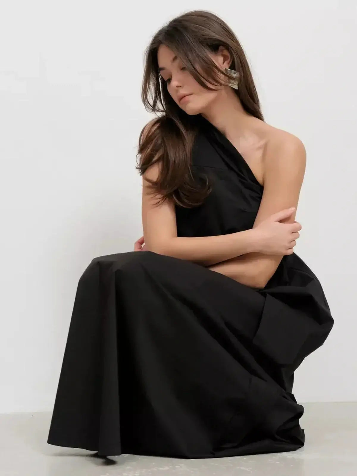 Black one-shoulder maxi dress featuring draped details, ideal for sophisticated evening occasions.