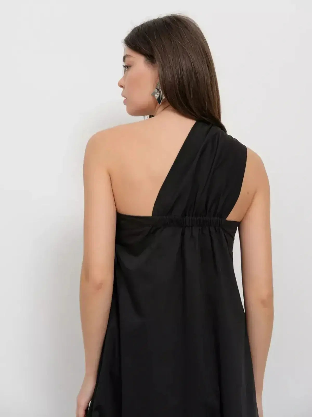 Noir Fold Maxi Dress featuring a one-shoulder design and elegant draping from the back view.