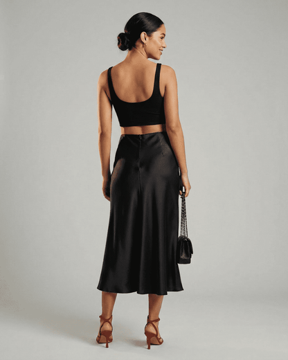 Model showcasing the Noirelle Midi Skirt by Lauven, featuring a sleek satin mermaid design in classic black.