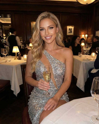 Nova Mini Dress by Lauven worn by a woman in a restaurant, showcasing silver sequins and a stylish one-shoulder design.