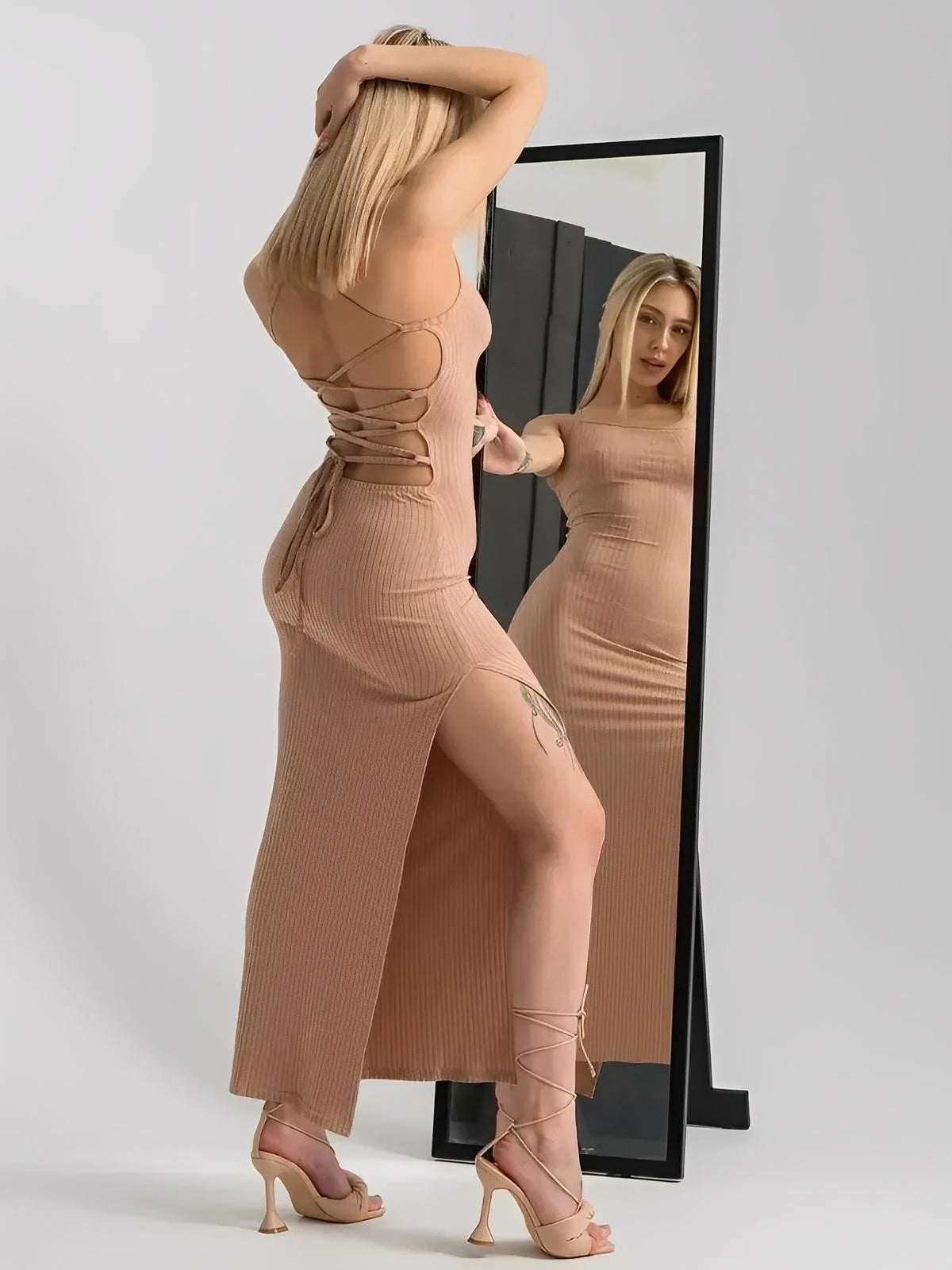 Model showcasing a Nude Lace Midi Dress with corset back, hugging curves, and thigh-high slit, reflected in a mirror.