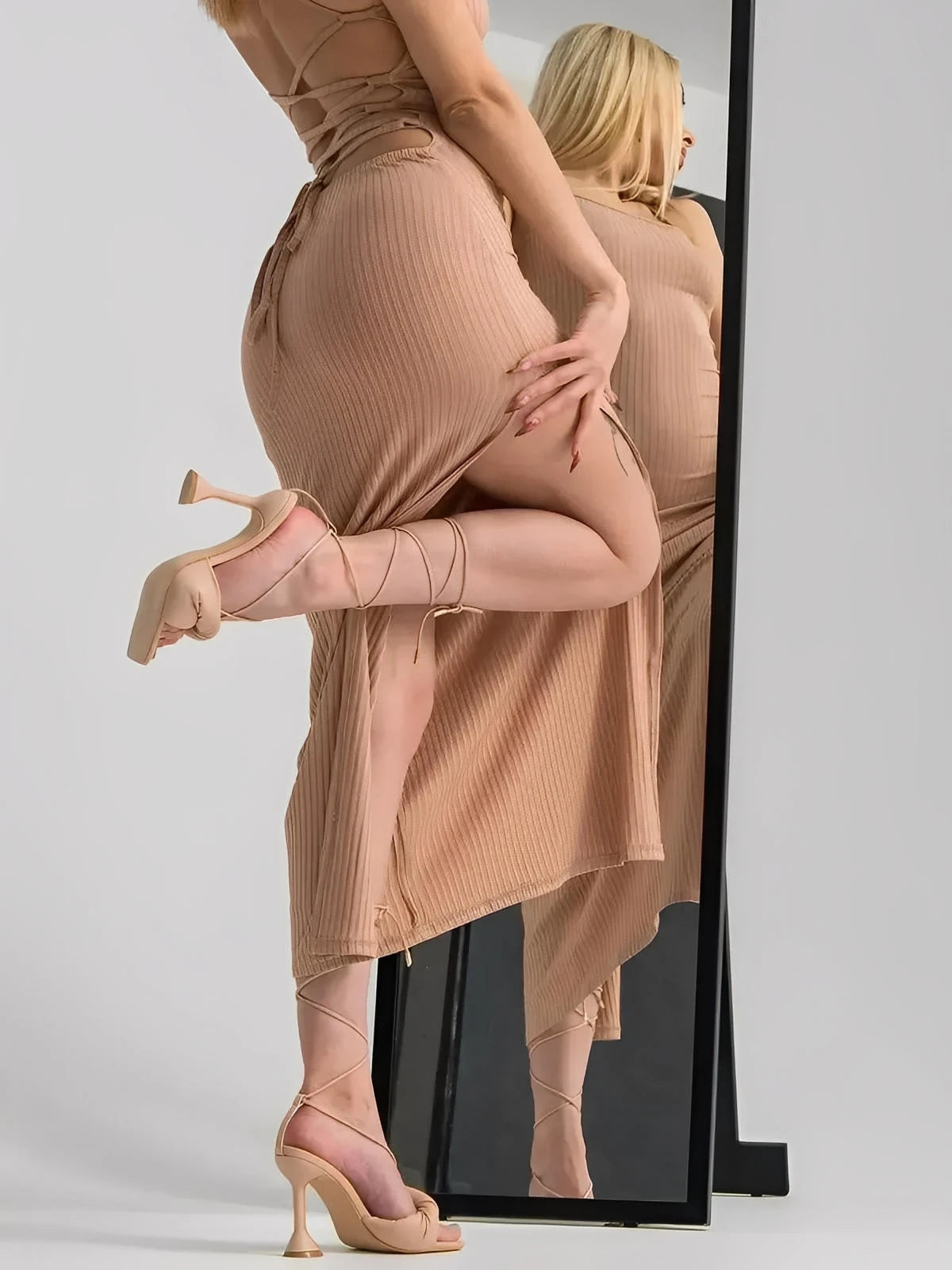 Model showcasing a nude lace midi dress with a sleek ribbed fit and thigh-high slit, styled with strappy heels.