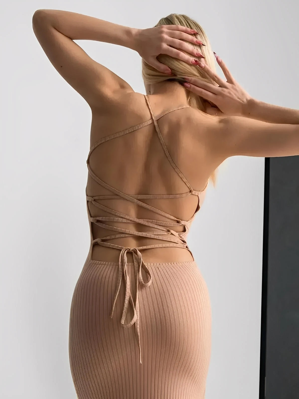 Back view of a model in a nude lace midi dress showcasing the adjustable lace-up corset design.
