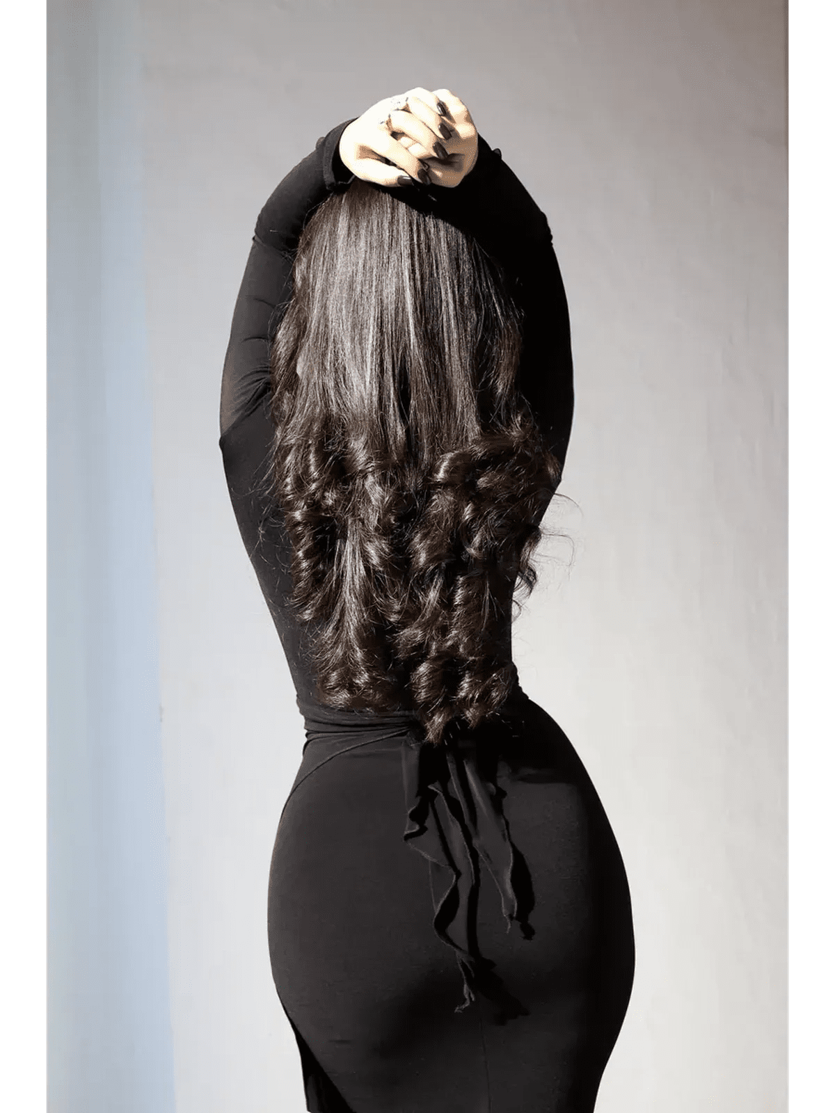 Model showcasing the back of an Obsidian Drape Maxi Dress with gathered detail and flowing hair.