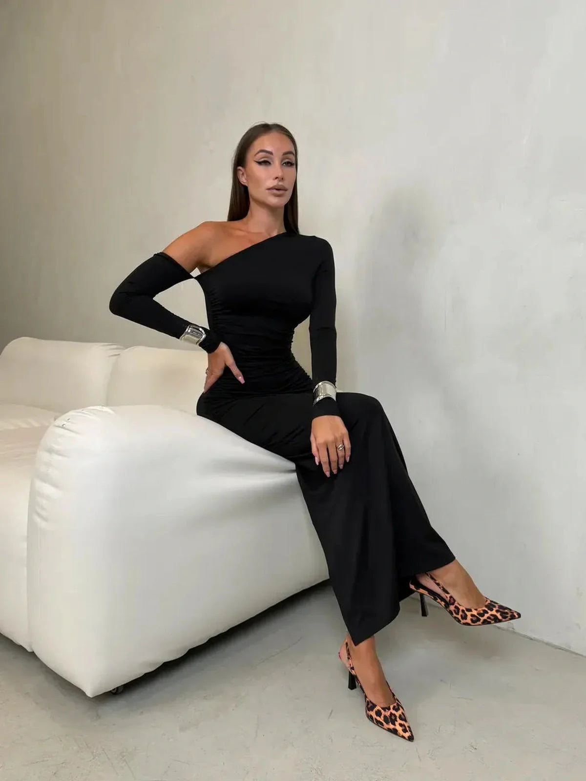 Model in Obsidian Maxi Dress, showcasing asymmetric silhouette and sleek elegance, styled with chic leopard-print heels.