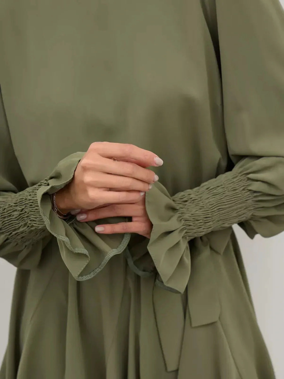 Close-up of Olive Luxe Mini Dress showcasing smocked sleeves and ruffled cuffs in sophisticated olive green.