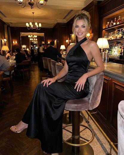 Lauven Orion Maxi Dress featuring a sleek halter neck design and bodycon silhouette in black, worn at a stylish venue.