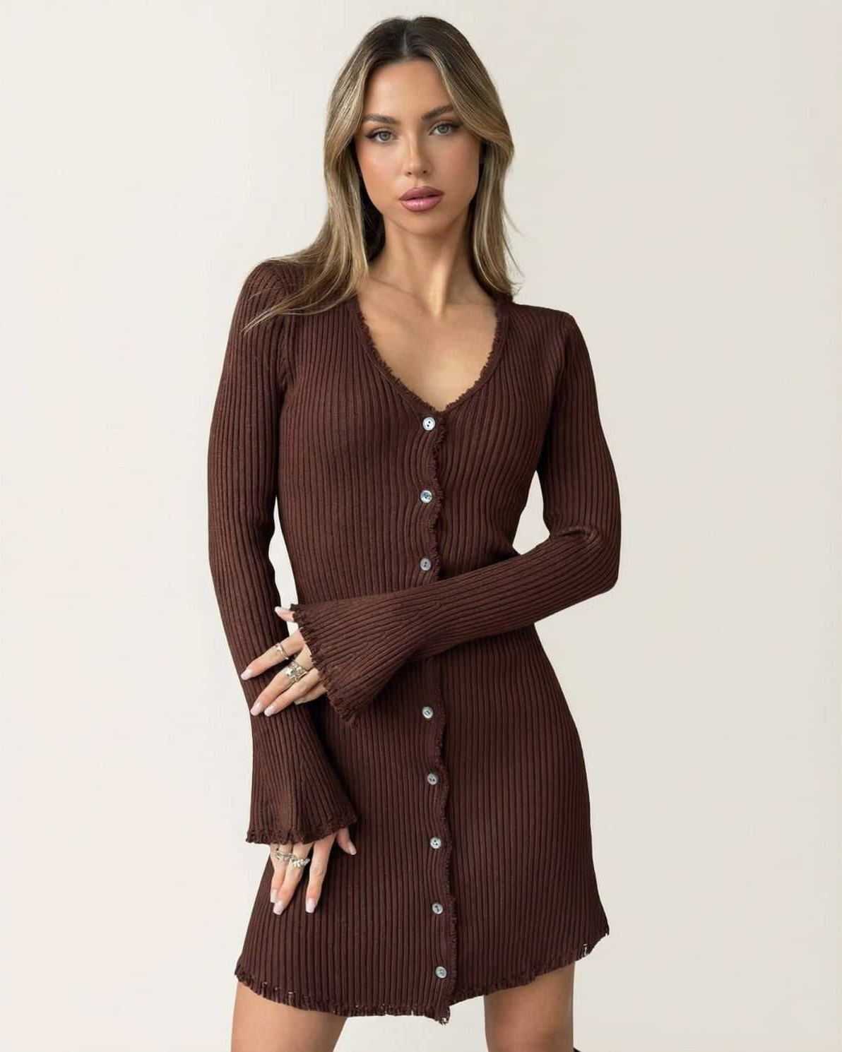 Model wearing the Orion Mini Dress by Lauven, a ribbed bodycon mini dress with flare sleeves and button details in deep chocolate brown.