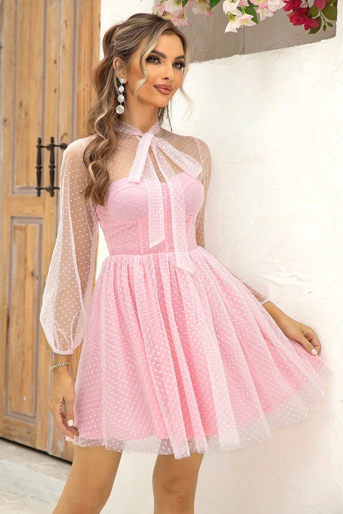 Model wearing a pink polka dot mesh Pearl Mini Dress with a sweetheart neckline and sheer bow tie collar.
