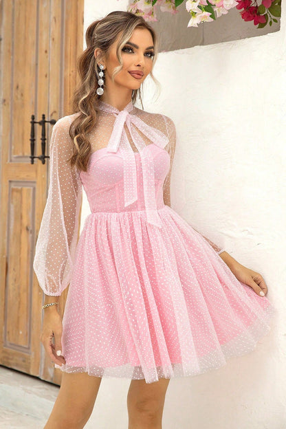 Model wearing a pink polka dot mesh Pearl Mini Dress with a sweetheart neckline and sheer bow tie collar.