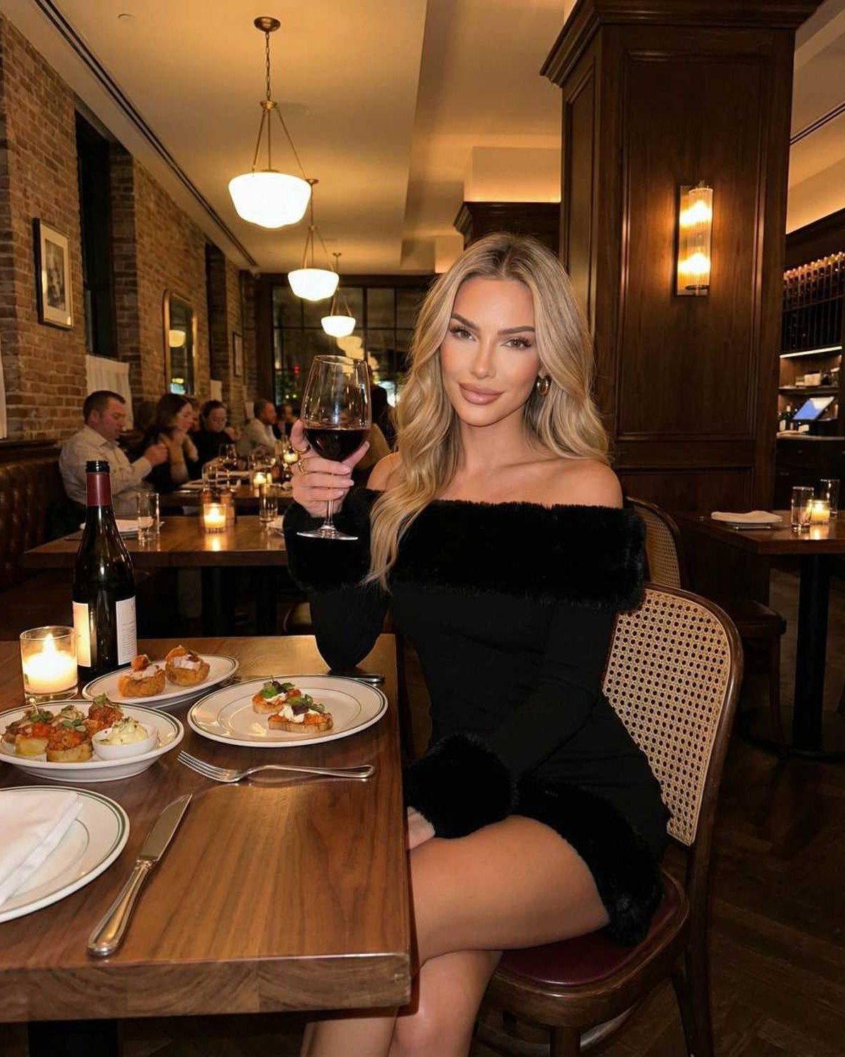 Luna Mini Dress with faux fur trim, worn by a woman holding wine in a restaurant setting, showcasing autumn elegance.