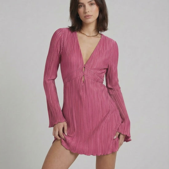 Aurora Mini Dress by Lauven in vibrant pink, featuring pleated fabric, long sleeves, and a deep V-neckline.