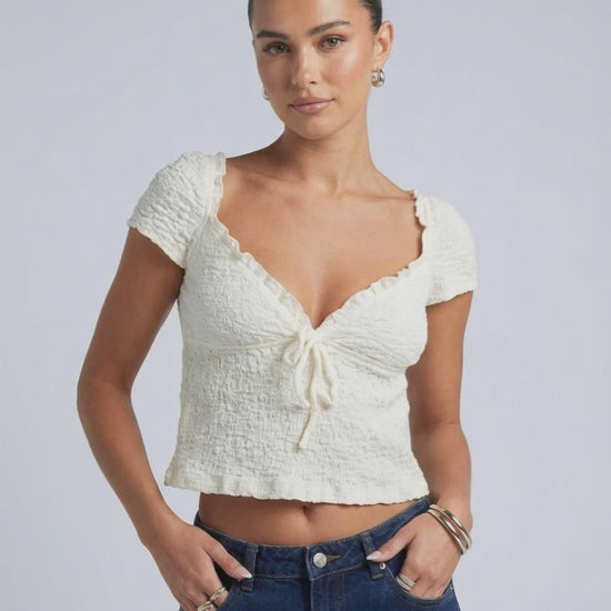 Model wearing Elara Tie Top by Lauven, a ruched V-neck crop blouse with adjustable tie detail.