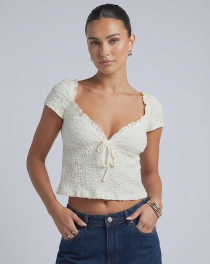 Model wearing Elara Tie Top by Lauven, a ruched V-neck crop blouse with adjustable tie detail.