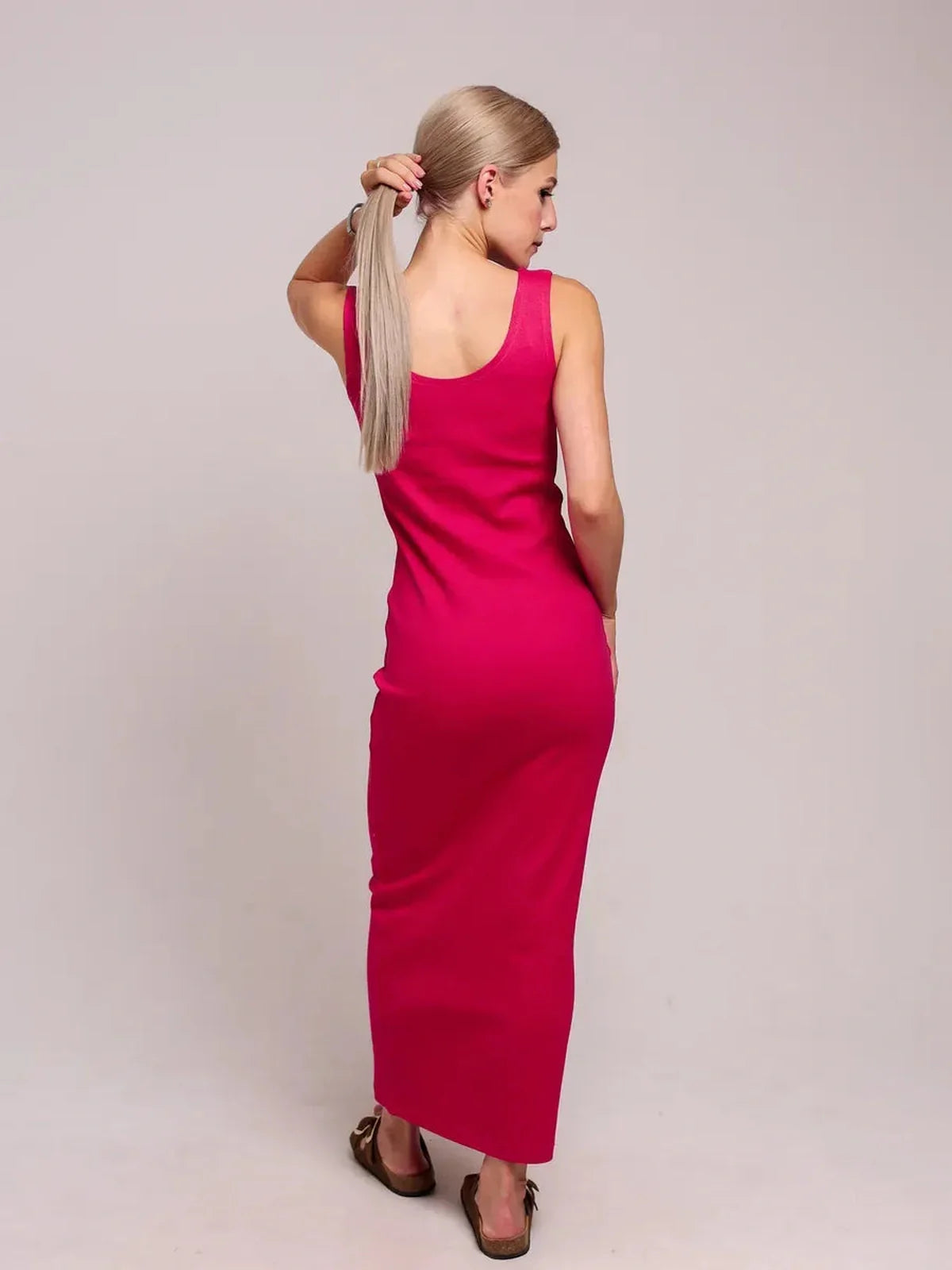Back view of a woman in a fuchsia Radiance Maxi Dress, showcasing its sleek design and elegant silhouette.