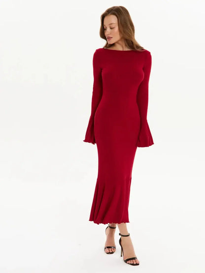 Model wearing a red velvet flare midi dress with long sleeves and flared cuffs for formal events.