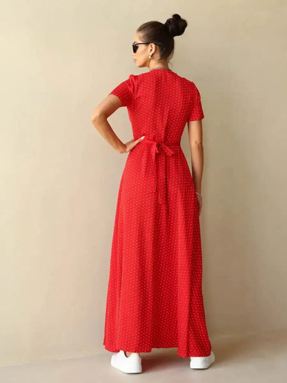 Model showcasing the back view of the Ruby Grace Maxi Dress in red polka dots with a tie waist and flowing silhouette.