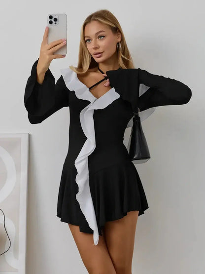 Model wearing the Ruffle Affair mini dress in black and white, showcasing long sleeves and flared cuffs.