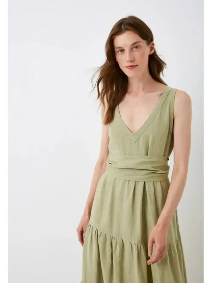 Model wearing Sage Whisper Maxi Dress in olive, featuring a V-neckline and gathered tiers for summer elegance.