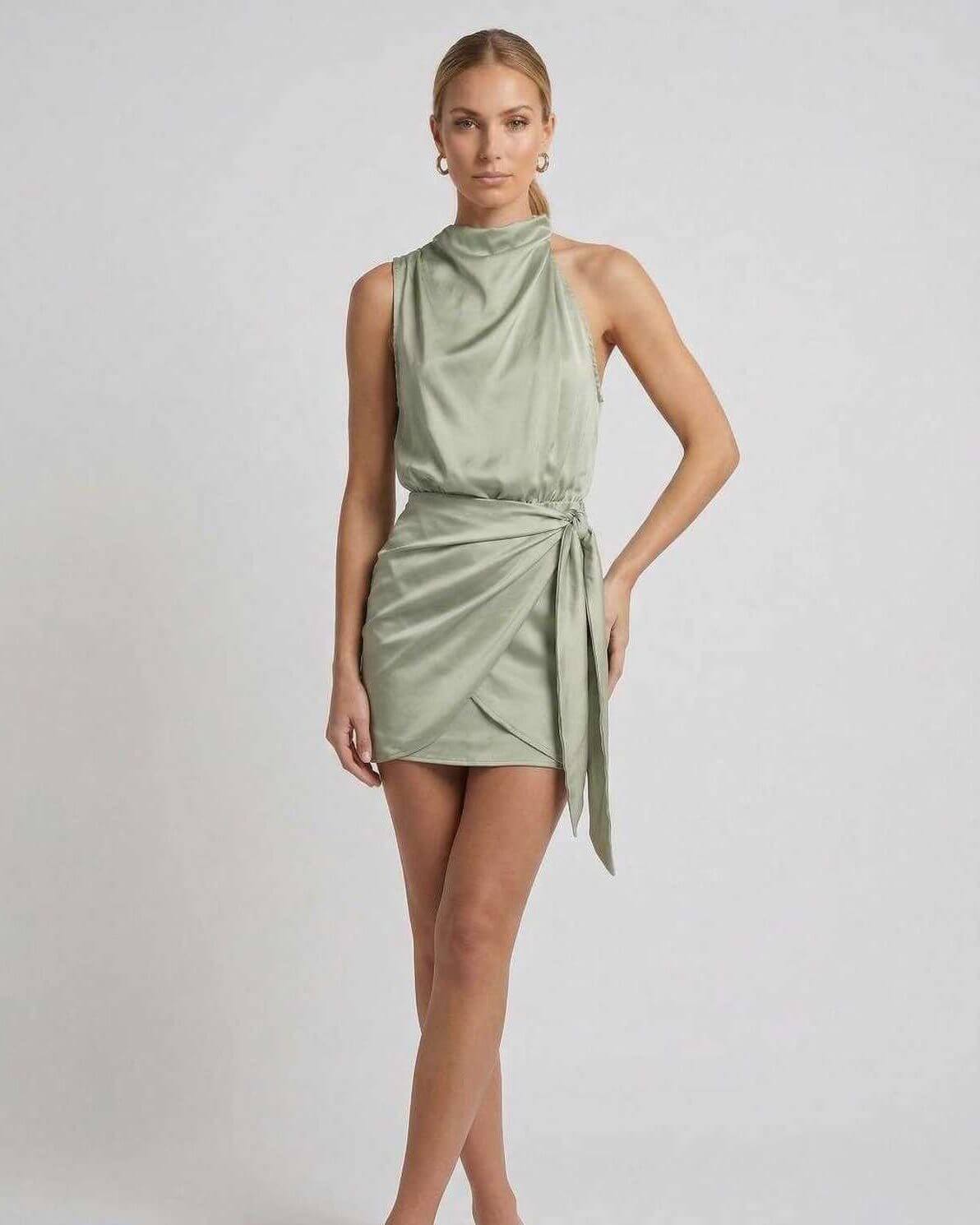 Sahara Mini Dress by Lauven in soft sage green with draped high neck and wrap tie detail.