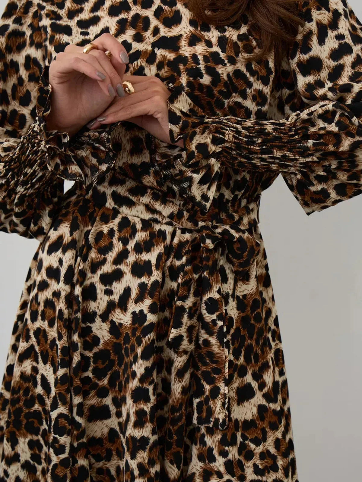 Savannah Mini Dress featuring bold leopard print, ruffle accents, and a waist-defining tie belt for a stylish look.