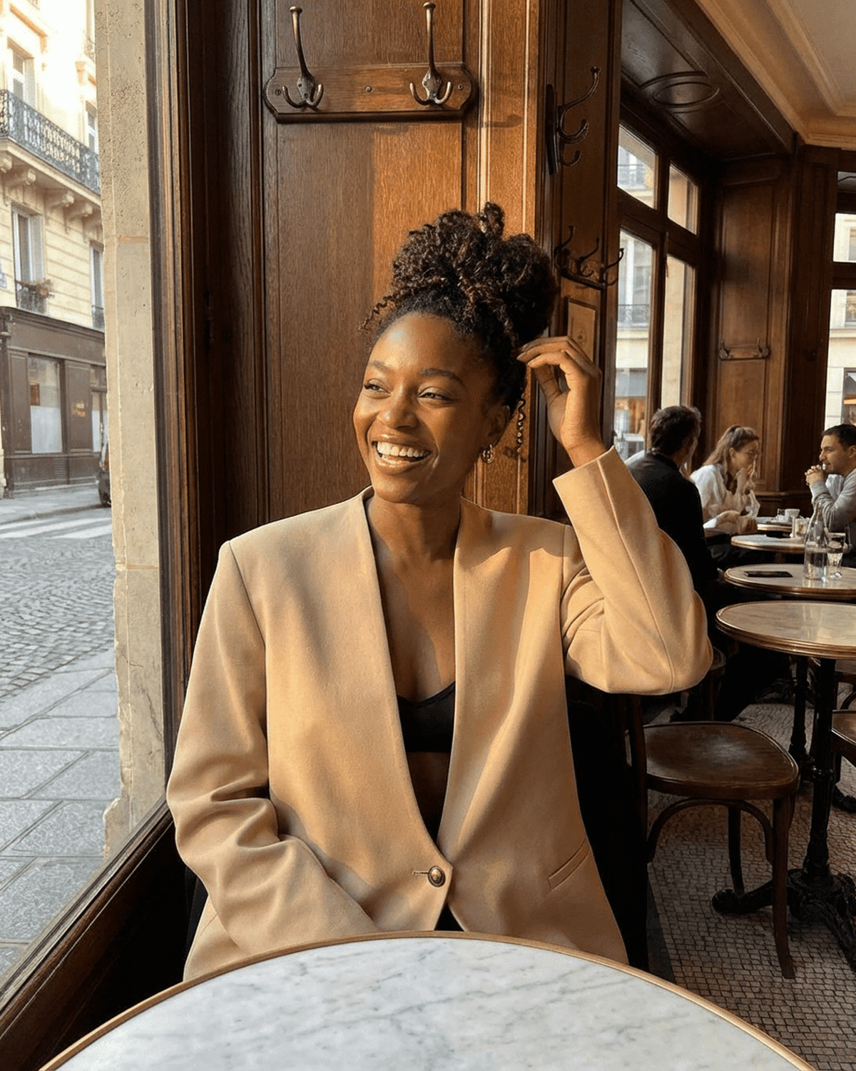 Savona Blazer by Lauven worn by a smiling woman in a café setting, showcasing a chic, tailored look.