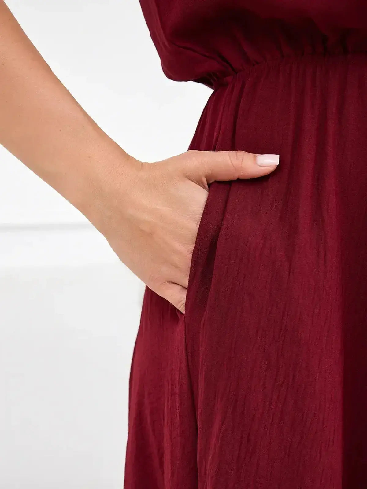 Close-up of a hand in the pocket of a burgundy maxi dress, highlighting the dress's stylish and functional design.