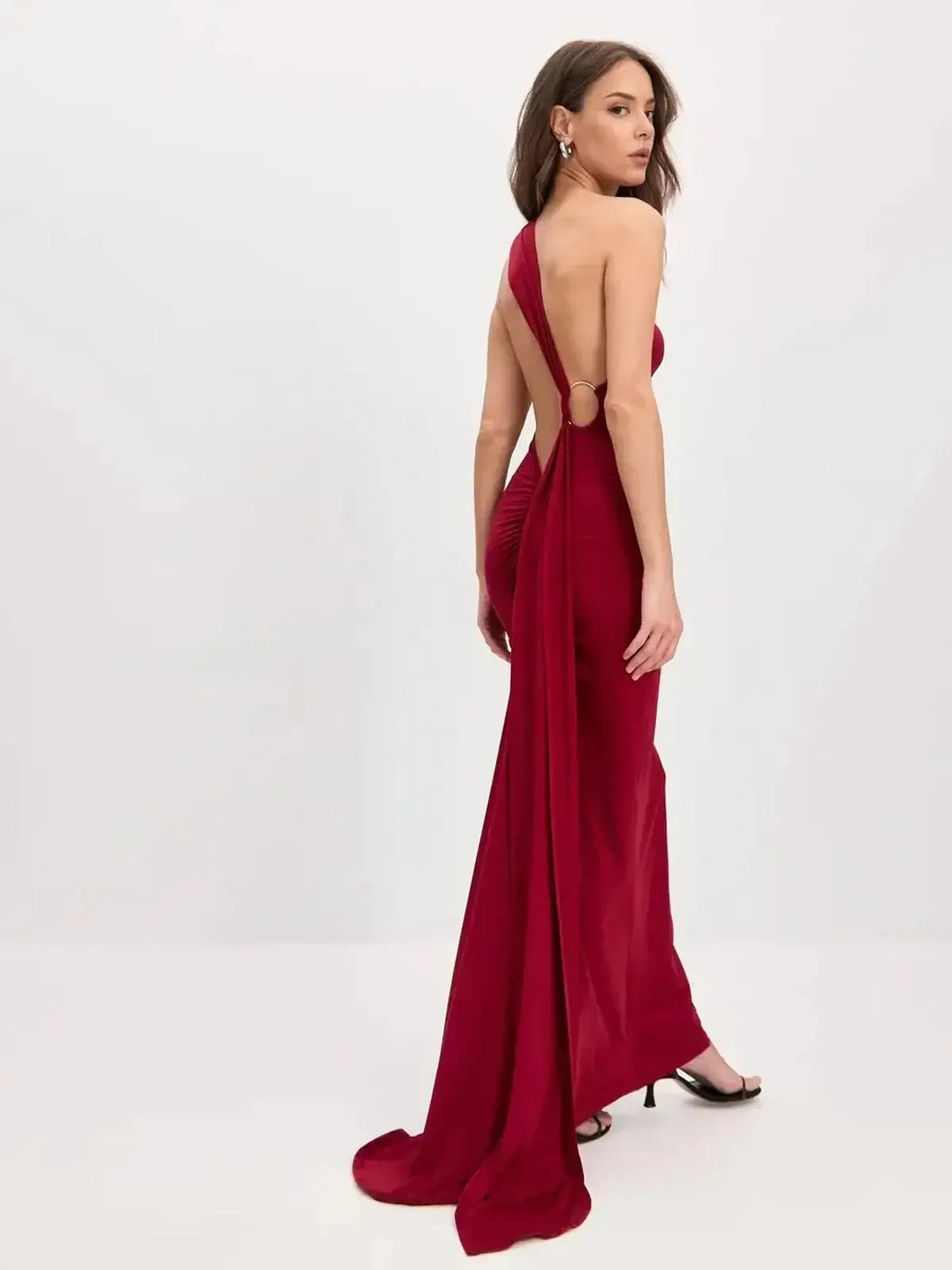 Woman in a sculpted flame maxi dress, showcasing a sleek one-shoulder design and flowing scarf detail in bold red.