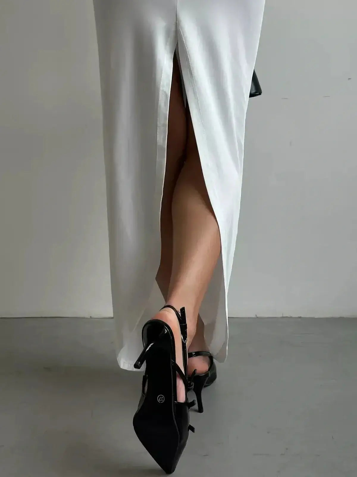 Sculpted Glow Maxi Dress featuring a thigh-high slit and elegant black strappy heels, showcasing sophisticated summer style.