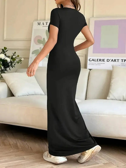 Woman in a sleek black Sculpted Grace Maxi Dress showcasing a modern, minimalist style in a stylish living room setting.