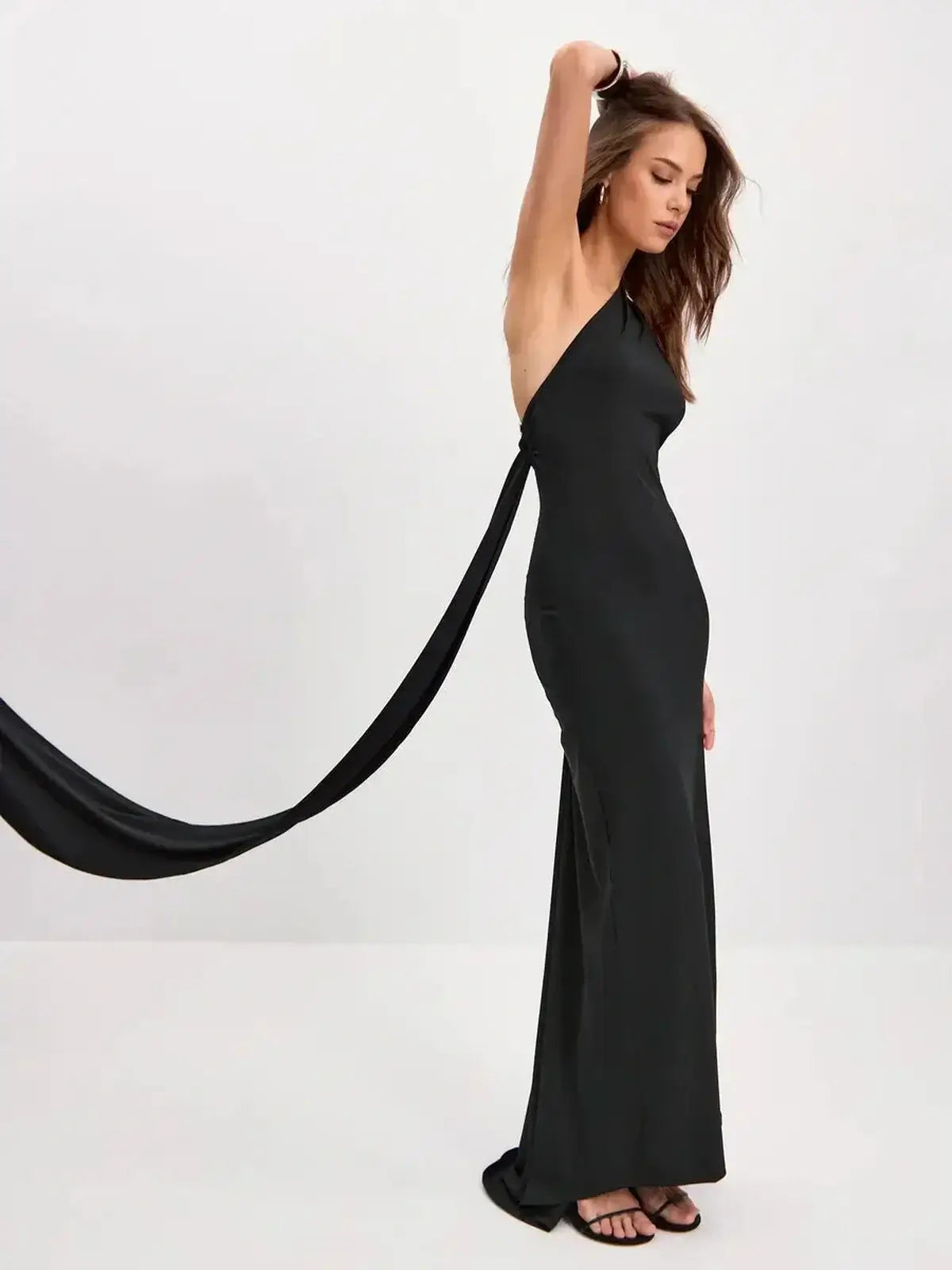 Model wearing the Sculpted Grace Maxi Dress, a sleek black one-shoulder gown with luxe draping detail.