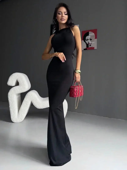 Model showcasing a Sculpted Noir Maxi Dress, featuring a sleek silhouette and elegant bow detail, set against an artistic background.