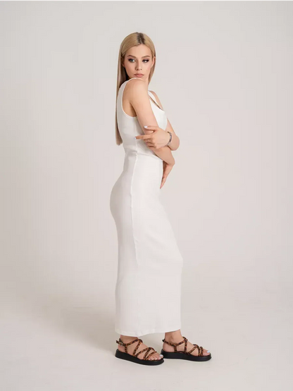 Model showcasing the Sculptura Maxi Dress, a sleek ribbed white dress, paired with stylish sandals.