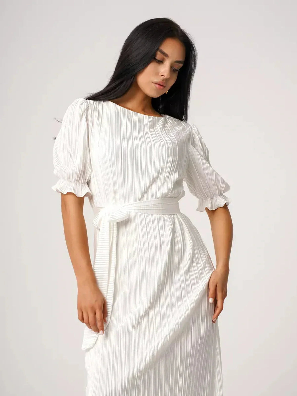 Elegant woman in a pleated white Seraphine Maxi Dress showcasing refined silhouette and summer chic style.
