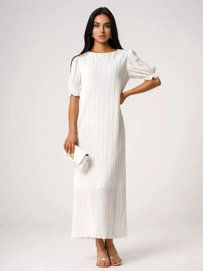 Elegant woman in a white pleated maxi dress, showcasing refined silhouette and summer style.