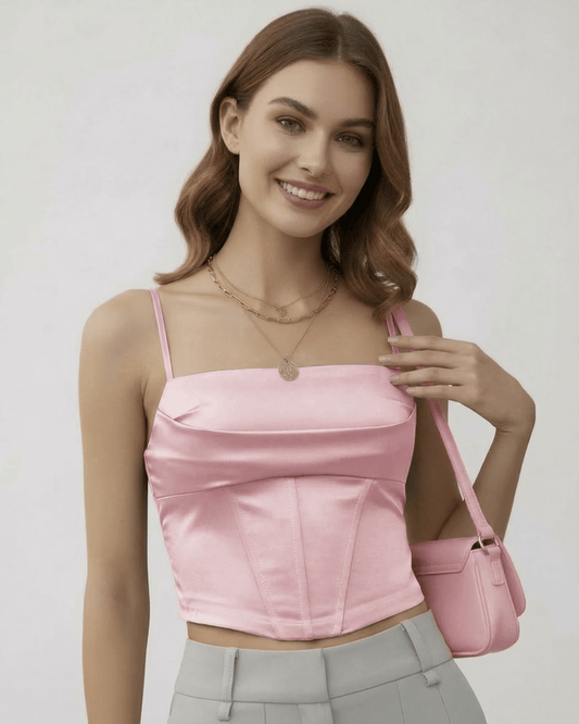 Model wearing Lauven Serena Corset Top in soft pink satin with refined structure and stylish accessories.