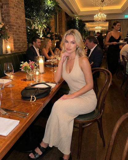 Woman wearing Serena Maxi Dress by Lauven at a classy dining setting, showcasing elegant ribbed knit design in beige.