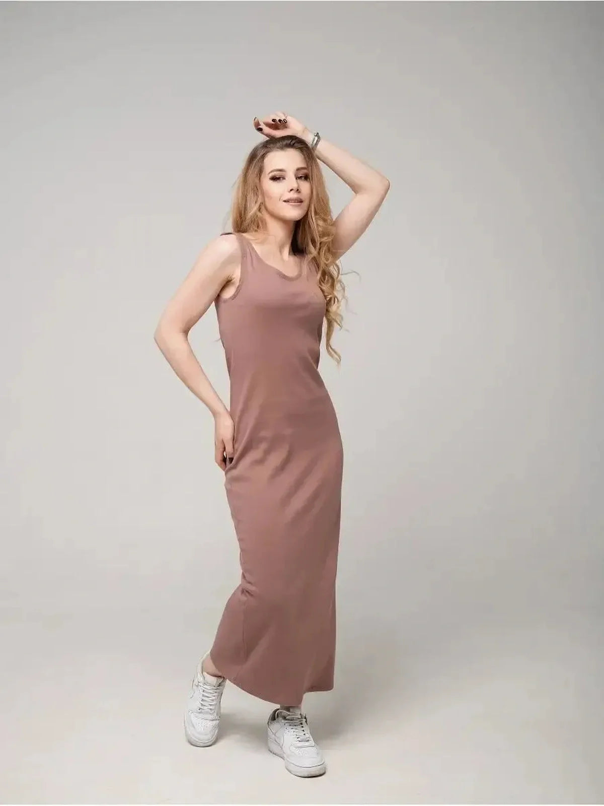 Woman in a sleeveless, mauve Serene Flow Maxi Dress with a relaxed silhouette and casual white sneakers.