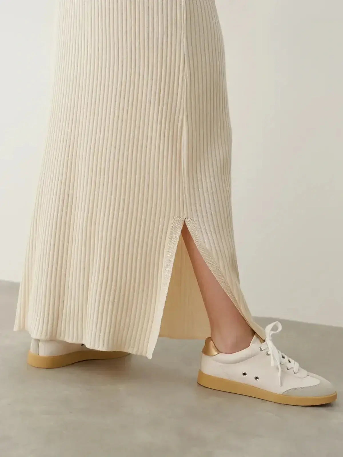 Detail of the Serene Rib Maxi Dress showcasing a side slit, paired with stylish white sneakers, perfect for summer wear.