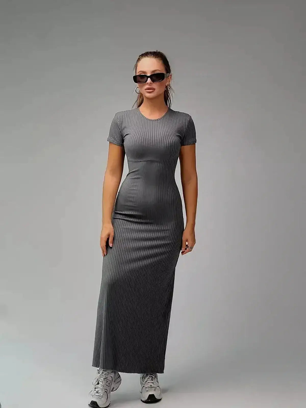 Model wearing a sleek gray Shadow Curve Maxi Dress with sunglasses, showcasing a figure-hugging silhouette and modern style.