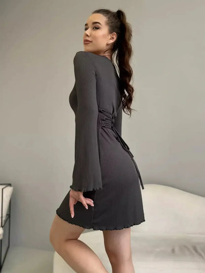 Stylish woman in a grey mini dress with long sleeves, perfect for summer events and cocktails.