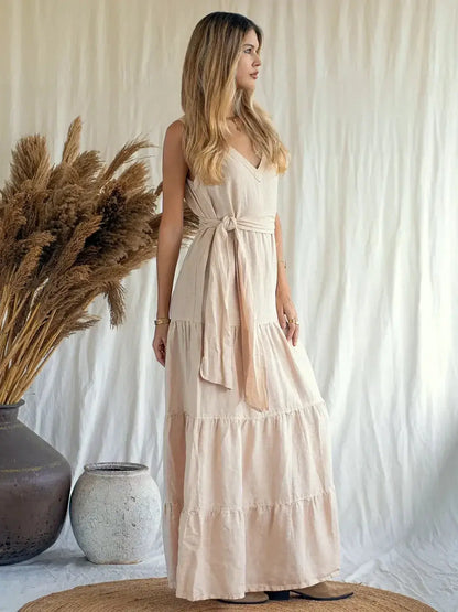 Stylish woman modeling a sleeveless Sierra Maxi Dress in linen, featuring a refined V-neckline and self-tie belt.