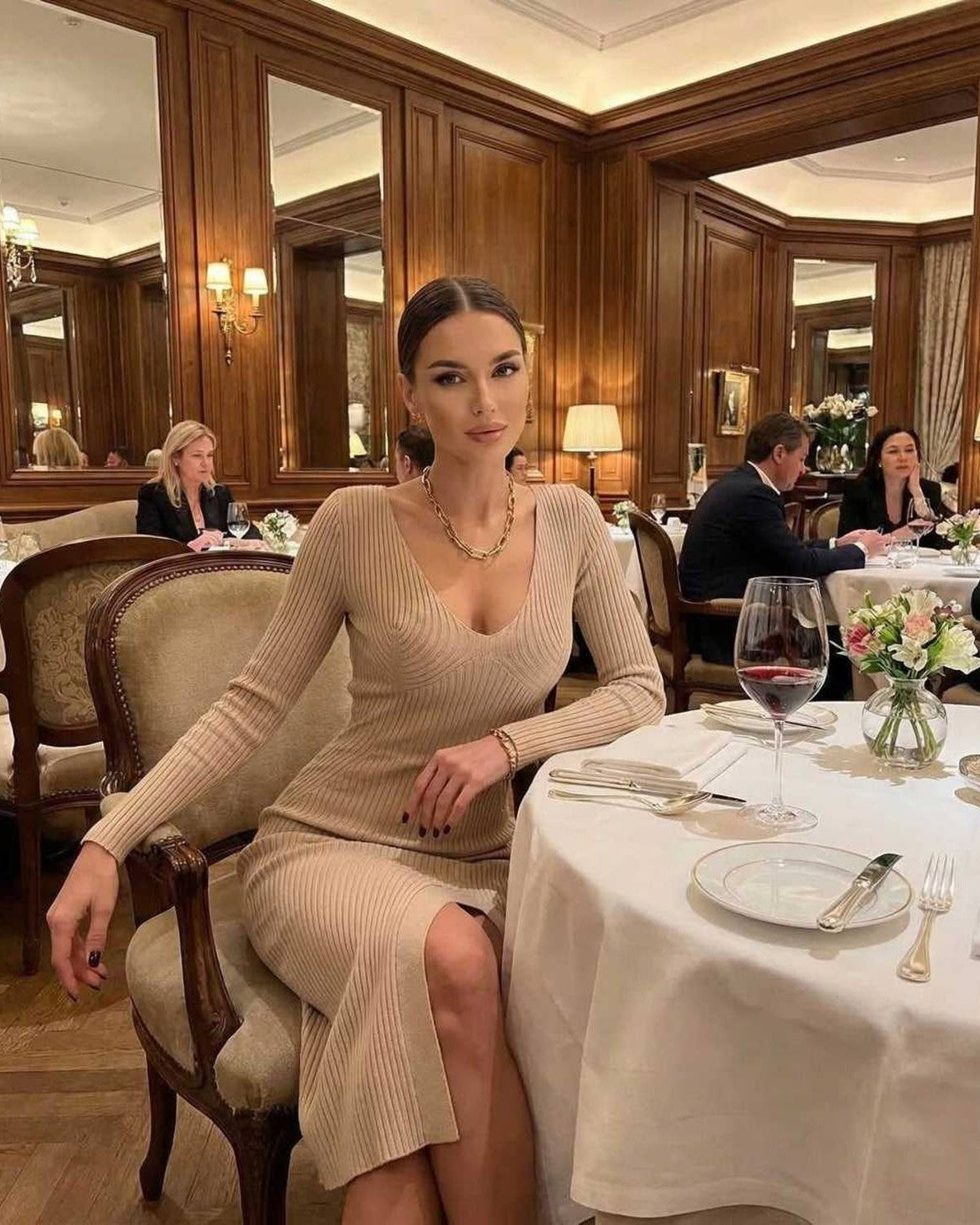 Sierra Midi Dress by Lauven, a sleek ribbed knit pencil dress featuring a V-neck, worn at an elegant dining setting.