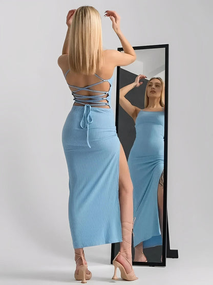 Model wearing Sky Lace Midi Dress with open corset back and high side slit, seen in front of a mirror.