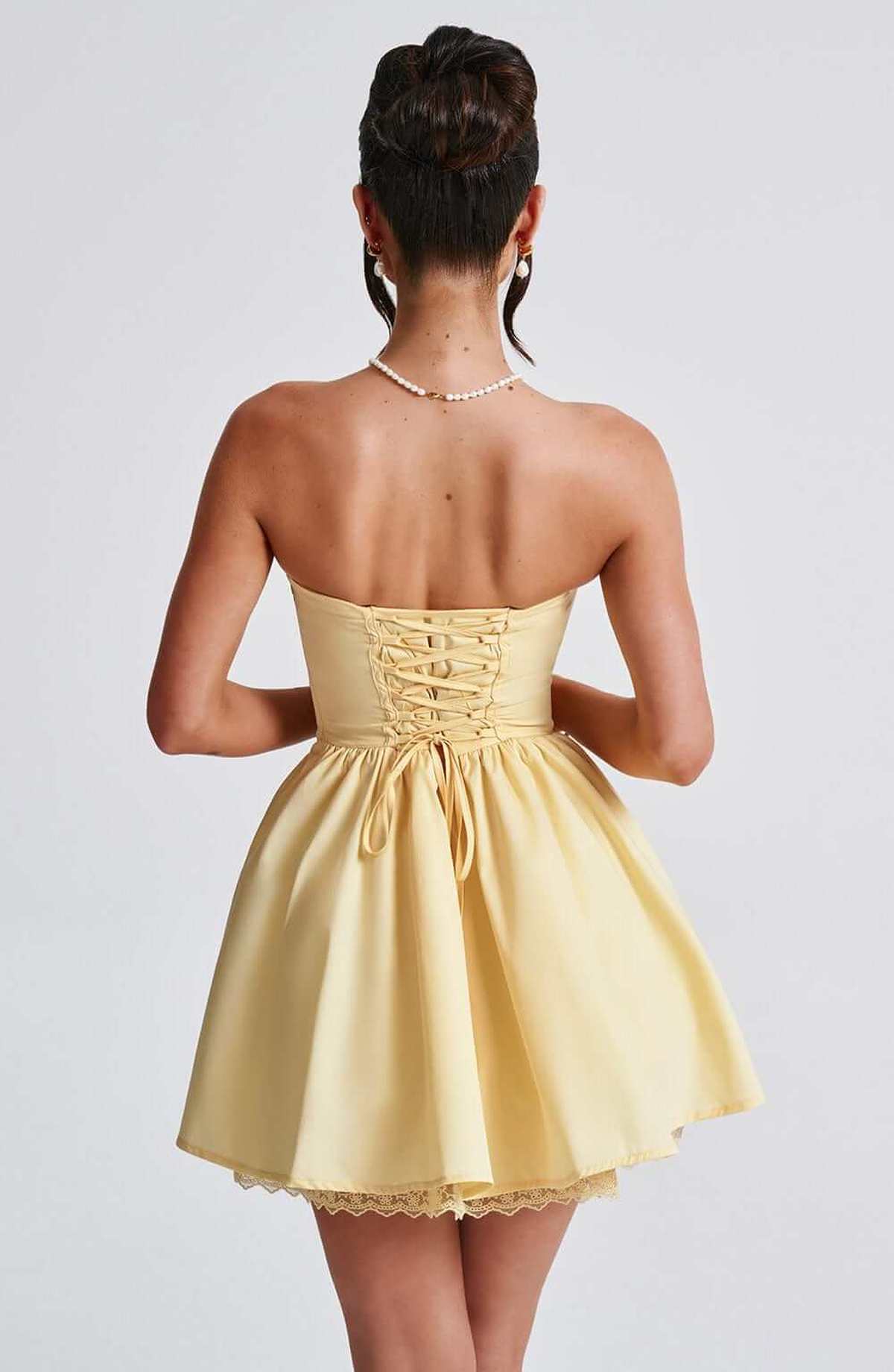 Back view of a yellow Skye Mini Dress with a corset design, perfect for weddings, proms, and summer parties.